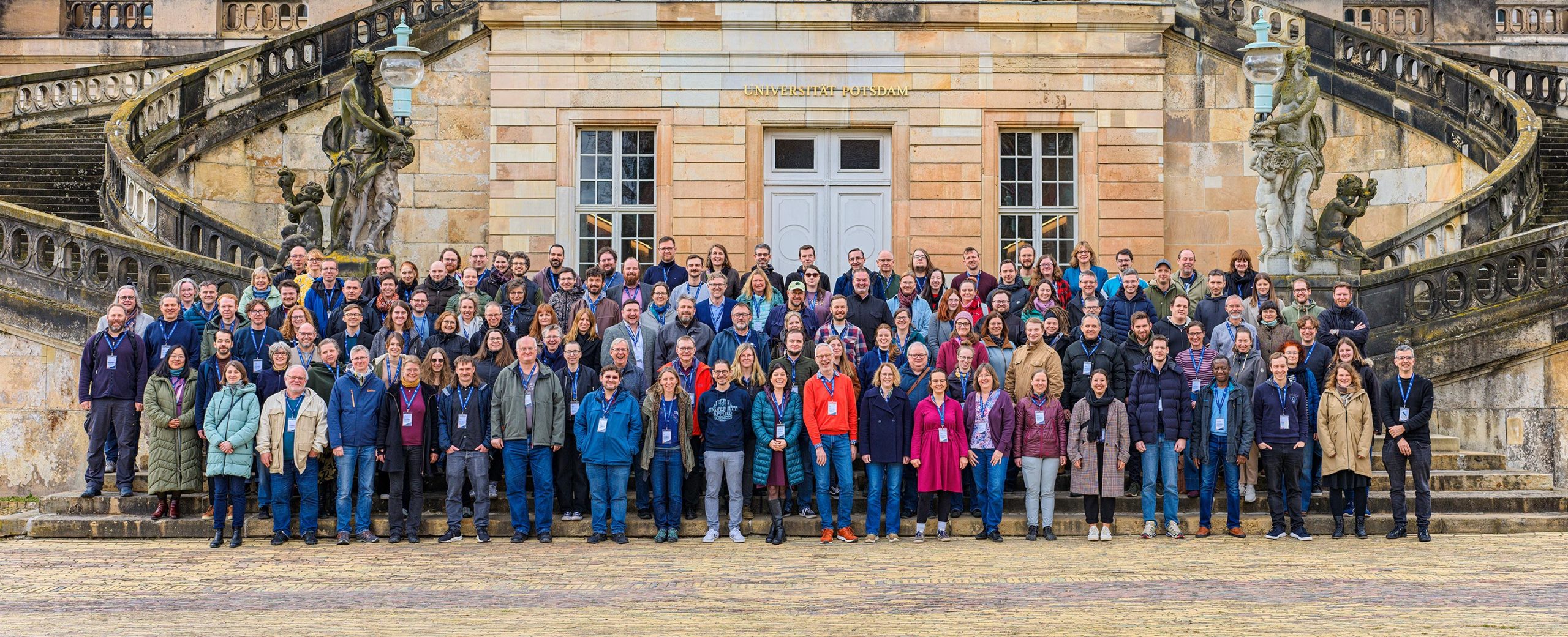2025_03_12_Moodle_Hochschultreffen_Gruppenfoto_ErnstKaczynski_Breitbild_B_01030-1 Gruppenfoto aller Teilnehmenden vor dem Neuen Palais